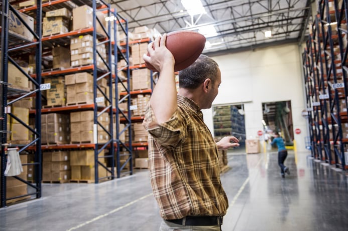 warehouse-employees-playing-catch-with-an-american-4CFPBN2